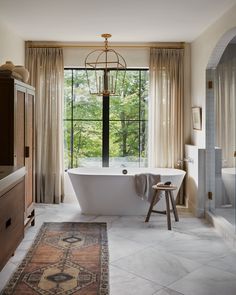 a bathroom with a tub, rug and large window in it's center area