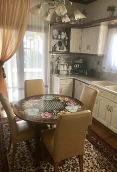 a dining room table and chairs in front of a window with curtains on the windowsill