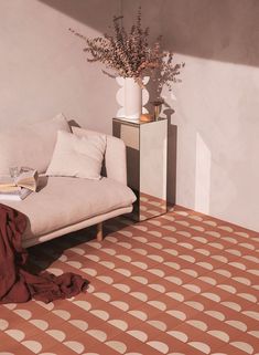 a white couch sitting next to a vase with flowers in it on top of a table