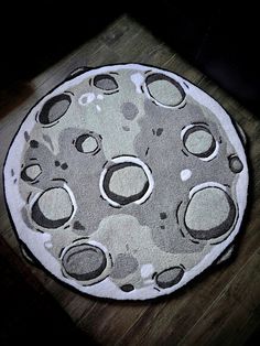 a round rug with black and white circles on the bottom is sitting on a wooden floor