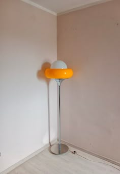 a floor lamp sitting on top of a hard wood floor next to a white wall