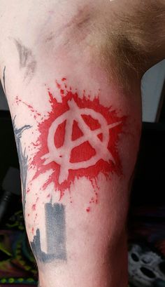 a man with a red and white tattoo on his arm that has the anarchy symbol painted on it