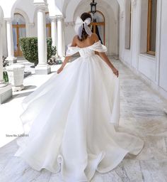 a woman in a white wedding dress is walking down the hall with her hand on her hip