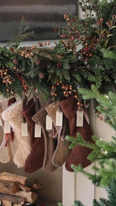 stockings hanging from a fireplace with christmas decorations on them and pine cones around the stockings