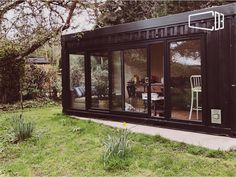 a black shipping container sitting on top of a lush green field