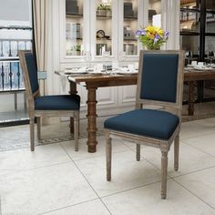 two blue chairs sitting at a table in a room with white walls and flooring