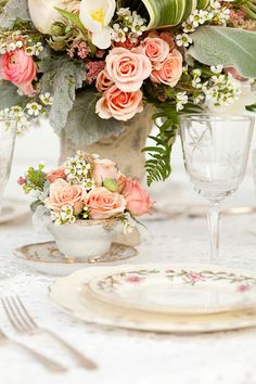 a vase filled with flowers sitting on top of a table next to glasses and plates