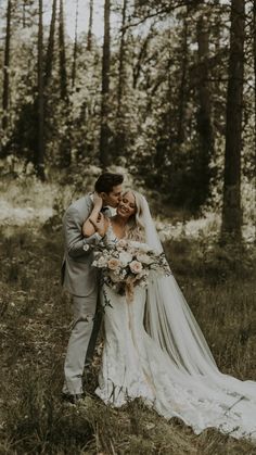 a bride and groom kissing in the woods