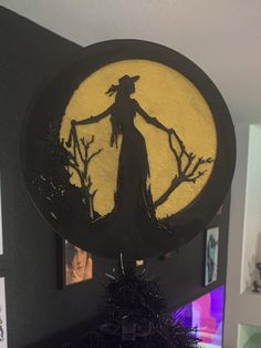 a black and yellow clock with a silhouette of a witch on it