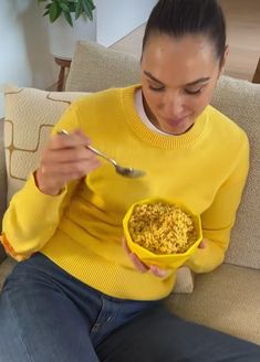 a woman sitting on a couch eating cereal