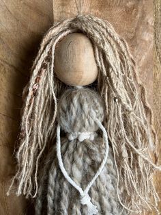 a wooden doll with dreadlocks on it's head sitting on a wood surface