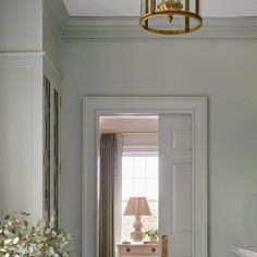 an open door leading to a living room with a lamp on the wall and flowers in vases