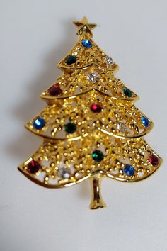 Christmas Tree Brooch in gold tone with colored rhinestones as the ornaments  Very pretty and light in weight.  It was a great find at an estate sale. Gold Christmas Holiday Brooch, Gold Christmas Brooches For Festive Occasion, Gold Holiday Brooch Jewelry, Mid Century Christmas, Owl Pendant, Calla Lily, Pin Badges, Gold Tone Metal, Vintage Signs