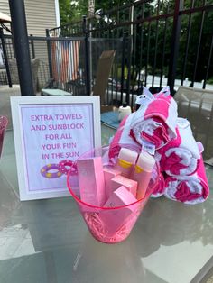 pink towels and personal care items are sitting on a table with a sign that says, extra towels and sunblock for all your fun in this summer