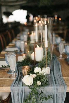 the table is set with candles, flowers and greenery for an elegant dinner party