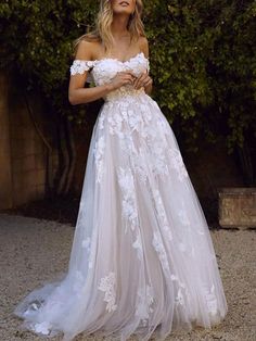 a woman in a white wedding dress posing for the camera with her hands on her hips