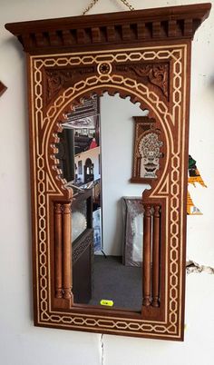 a mirror hanging on the wall with an ornate frame and wood decoration around it,