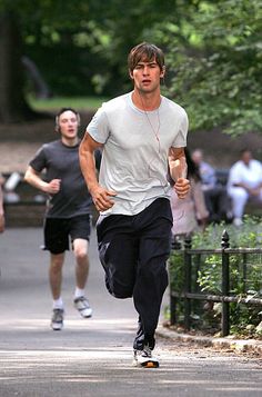 a man running down the street while listening to music on his headphones with other people in the background