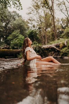 a woman sitting in the middle of a river with her legs crossed and looking up