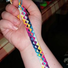 a person holding a colorful bracelet in their left hand with a toothbrush in the other hand