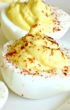 deviled eggs on a white plate with red sprinkles and seasoning