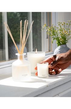 a person lighting candles on a window sill