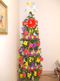 a decorated christmas tree in the corner of a room with a clock and letters on it