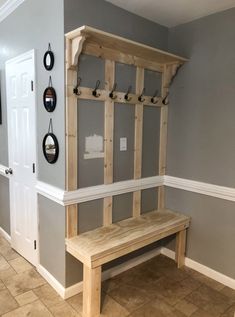 a wooden bench sitting in the middle of a room next to a wall with hooks on it