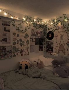 an unmade bed in a room with posters on the wall and lights strung above it