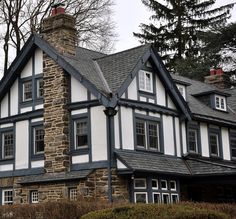 an old house with white and blue trim on the front, black roof and windows