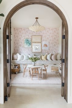 an archway leads into a dining room with floral wallpaper on the walls and white furniture