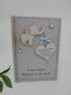 a card with an elephant holding a heart and star on the front, next to a plant