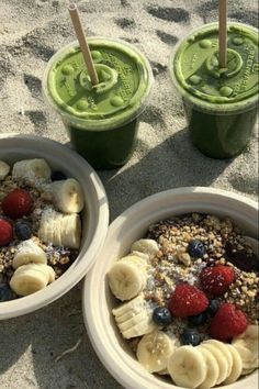 two cups filled with yogurt and fruit on the beach