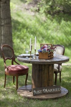 a wooden table with two chairs and a sign that says just married on it sitting in the grass