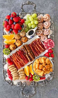 a platter filled with different types of food on top of a metal tray next to fruit