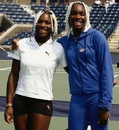 two female tennis players pose for a photo on the court in front of an empty bleachers