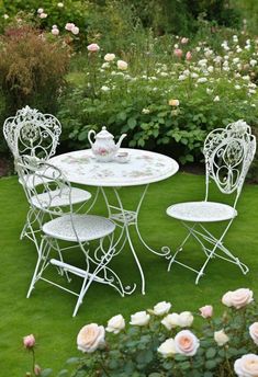 a white table and chairs sitting on top of a lush green grass covered garden area