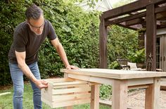 a man working on a table made out of pallets in the yard with his hands