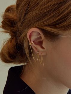 a close up of a person wearing gold ear cuffs with chains attached to the back of their ears