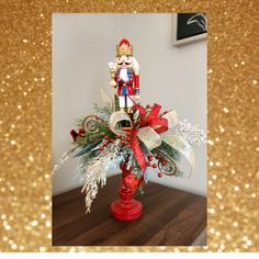 a nutcracker on top of a red vase filled with greenery