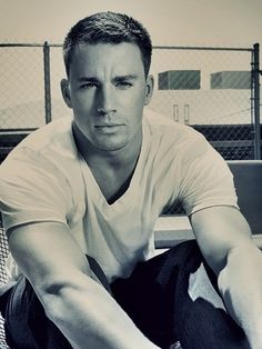 a black and white photo of a man sitting on a bench with his arms crossed