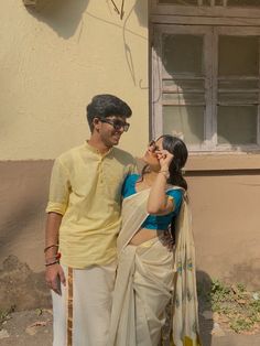 a man and woman standing next to each other in front of a building with windows