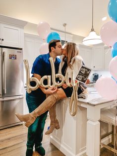 a man and woman kissing in the kitchen with balloons