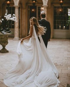 a woman in a wedding dress walking down the street with a man wearing a tuxedo