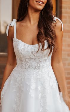 a woman in a white wedding dress posing for the camera with her hand on her hip