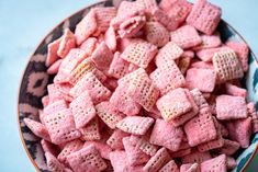 a bowl filled with pink cheetos sitting on top of a blue tablecloth