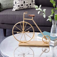 a wooden bicycle sitting on top of a table next to a vase with flowers in it