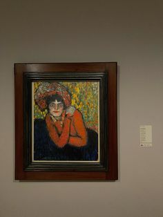 a painting is hanging on the wall next to a vase with an orange flower in it