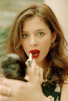 a woman with red lipstick on her lips is holding a black object in front of her face