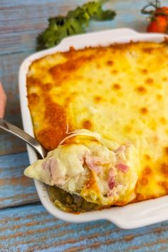 a casserole dish with meat and cheese in it on a blue wooden table